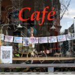 A window displaying a cafe sign featuring QR codes for small businesses.