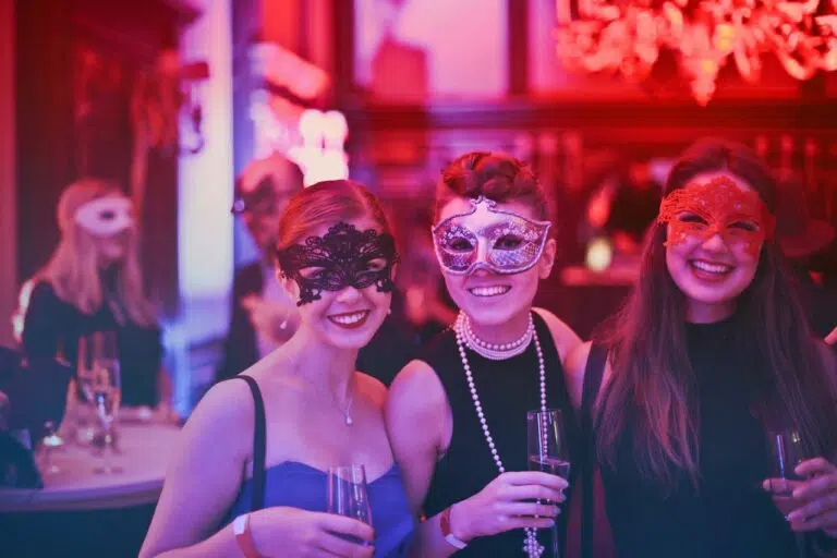 Three women wearing masks at a party, incorporating event marketing practices.