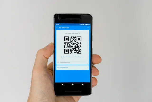 A person displaying a smartphone with a QR code, offering promotions and mobile app downloads.
